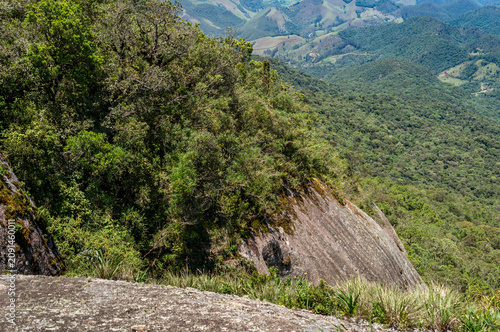 Rock cliff and Atlantic Forest vegetation overlooking mountain valleys scenic natural landscape view under summer morning sunny day in Monte Verde, Camanducaia, Minas Gerais - Brazil
