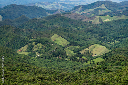 Rolling green hills and Atlantic Forest valleys seen from the summit of Pedra Redonda summit Monte Verde Highlands under summer morning sunny day. Monte verde, Camanducaia, Minas Gerais - Brazil.