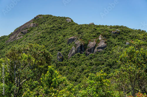 Granite rock formations rising above Atlantic Forest vegetation In Monte Verde highlands scenic mountain landscape under summer morning blue sky in Monte Verde, Camanducaia, Minas Gerais - Brazil.
