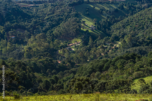 Panoramic view of green forested valleys and countryside retreats saw from Fazenda Off Road under summer afternoon sunny day in Monte Verde, Camanducaia, Minas Gerais - Brazil.
