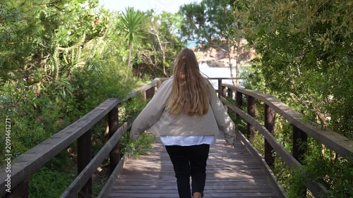 Woman Running on Wooden Boardwalk Through Coastal Forest to Beach