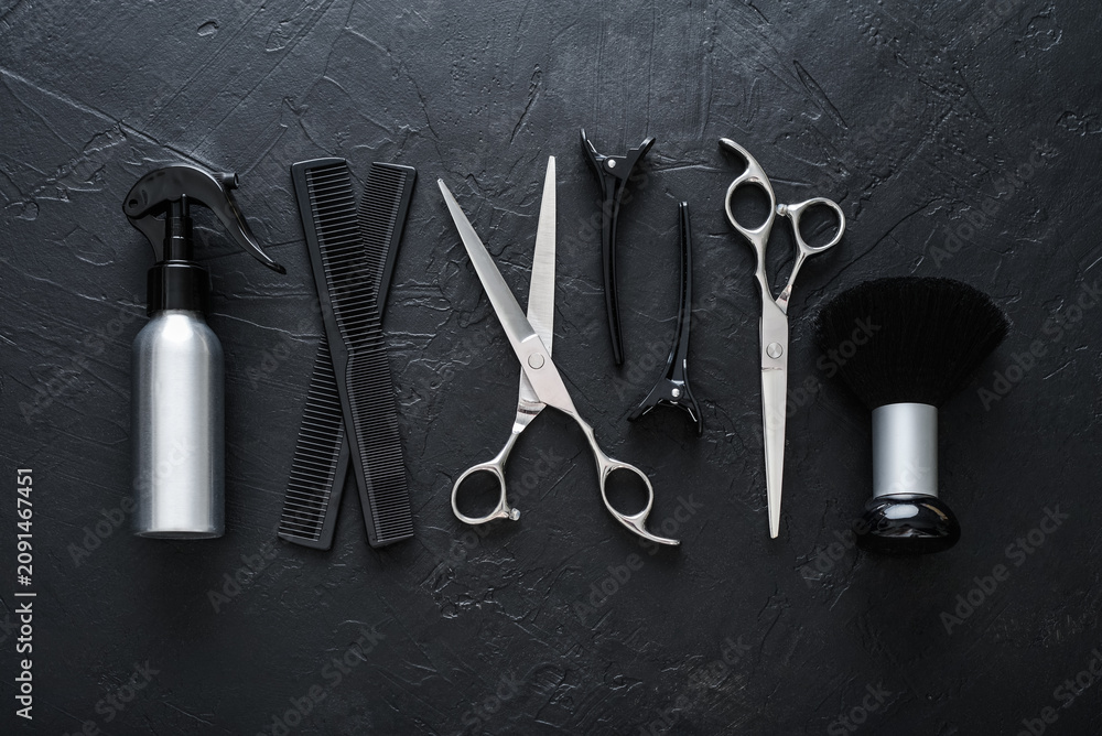 Fototapeta premium Professional hairdresser tools on a black textured concrete background.
