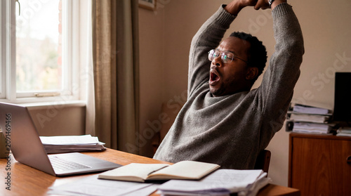 Elated scientist stretching his arms up in celebration at a laboratory desk