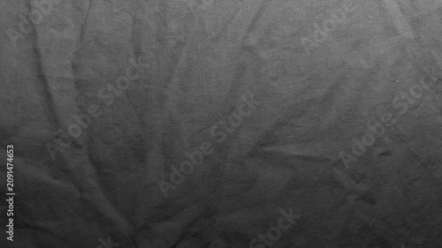 dark gray textured fabric background shows soft creases on fine woven linen material creating subtle monochrome shadows