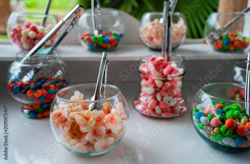 Foto Frascos de vidrio con surtido de caramelos y golosinas en mesa de dulces para bo