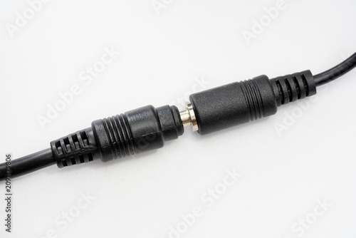 Black DC barrel power connectors joined on white background, closeup of male and female adapter cable coupler, low voltage electronics repair, extension lead and power supply safety concept, no people