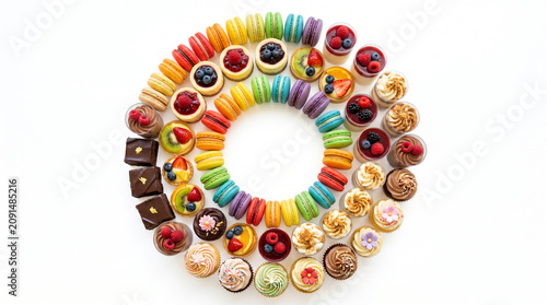Circular arrangement of assorted colorful desserts on white background