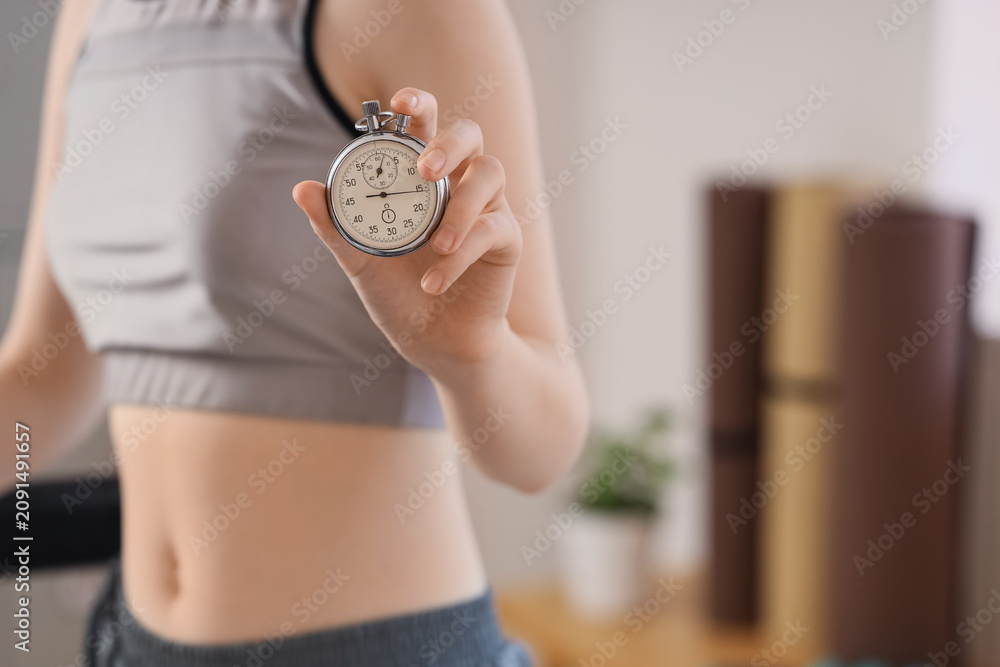 Obraz premium Woman in athletic wear holding a stopwatch, fitness and exercise timing, workout progress and personal training