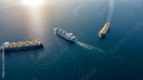 Aerial view of three LNG carriers sailing across the open sea in convoy, fleet of gas tankers with spherical Moss tanks transporting liquefied natural gas along a trade route