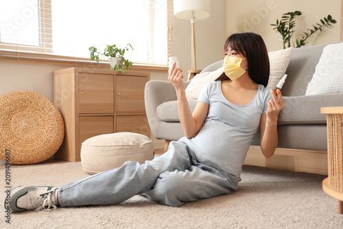 Pregnant Asian woman in yel...