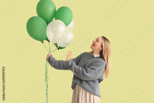 Young woman with balloons on green background