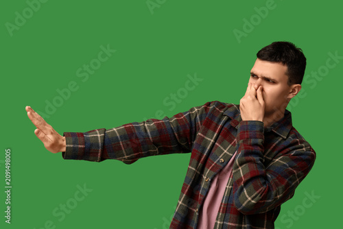 Cuadro en lienzo Handsome young man feeling bad smell on green background