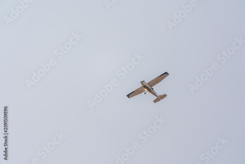 Small ultralight airplane with overhead wing and single propeller flying in sunset sky.