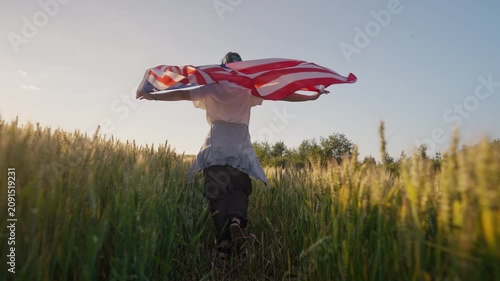 Happy woman runs in open field, holding the United States flag as it waves in breeze. Independence Day, American values, military support, political activism, national heritage. 