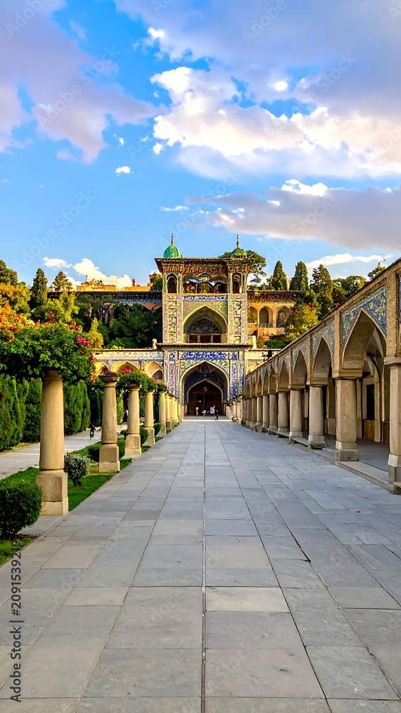 Obraz premium Long Pathway Leading to Ornate Arched Gate in Historical Courtyard Setting