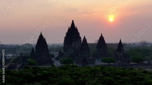 Aerial drone footage of Prambanan Temple in Yogyakarta, Indonesia at sunset with golden light illuminating the ancient cultural heritage site.