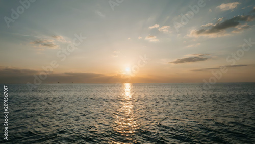 Golden sunset over calm ocean waters with soft clouds