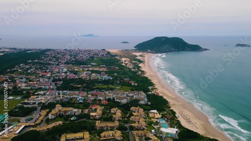 Aerial view of a coastal city nestled between lush forests and sandy dunes