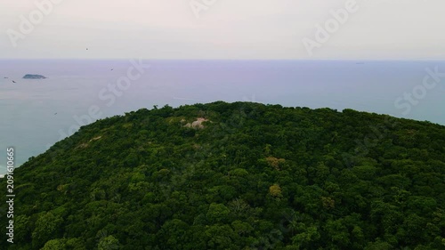 Aerial view of lush green mountains meeting the ocean with distant islands