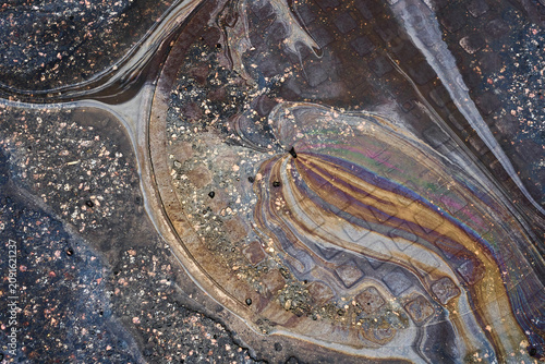 Oil Spills Create Colorful Patterns on Concrete Surface in Urban Area During Daytime Hours.