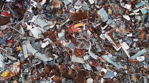 A horizontal drone top-down shot capturing a massive pile of industrial scrap metal, rusty iron, and materials waiting for sorting and sustainable recycling process in Preveza region, Greece.