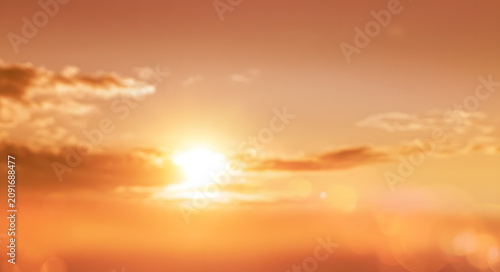 Abstract blurry sunset sky background with bright sun lens flare, glowing orange and yellow light, soft natural bokeh effect for summer evening nature landscape design