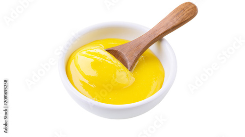 Fotografie Smooth yellow mustard in a white bowl with a wooden spoon, isolated on transpare