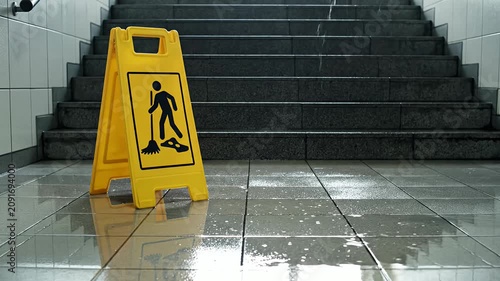 Yellow wet floor sign on stairs in hallway.