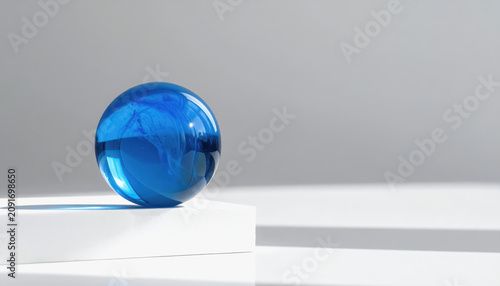 Abstract blue glass sphere with swirling patterns on a white pedestal casting shadows