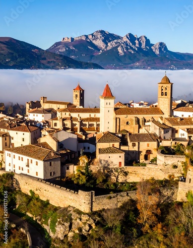 Medieval Village Perched on Hillside with Mountains in Background