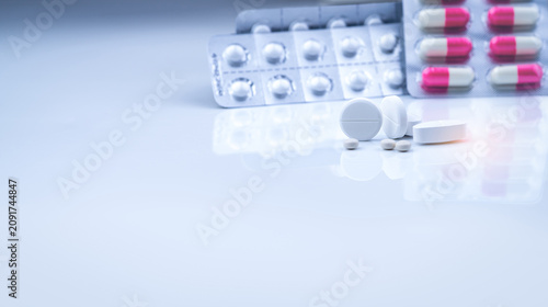 Foto White tablets pills on blurred white-pink capsules and round tablets in blister pack