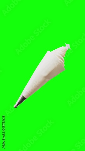 Plastic piping bag filled with creamy white frosting and metal star nozzle animated on green screen background, vertical video.