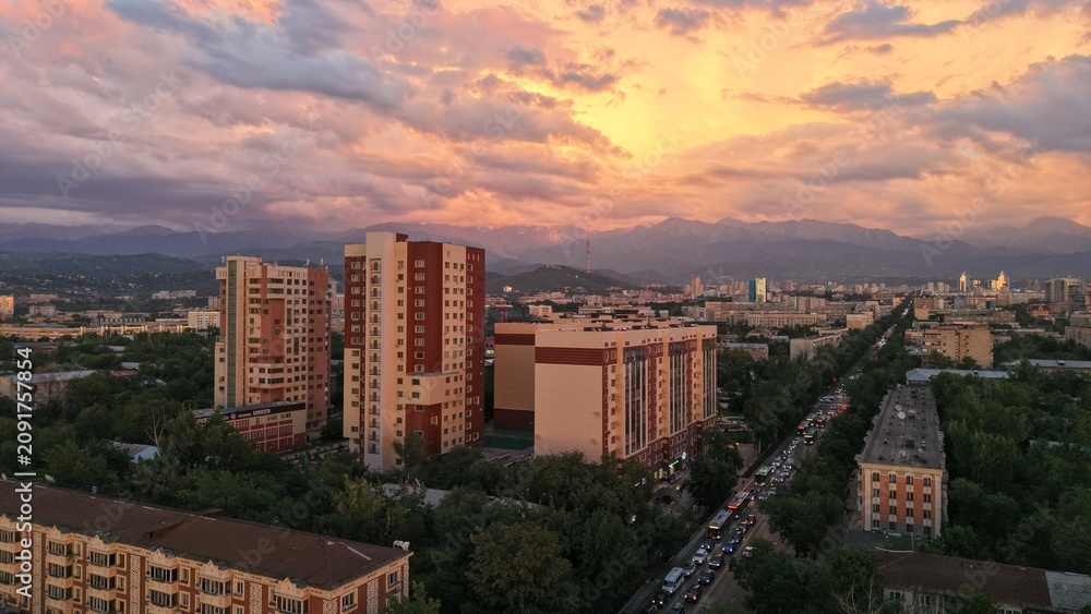 Fototapeta premium Aerial view of urban skyline at sunset with mountains in background