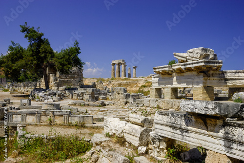 Ancient ruins of Corinth, Greece, with columns and stone structures under a clear blue sky.