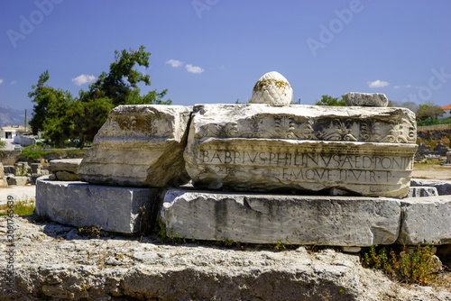 Ancient Roman ruins with inscription on stone blocks under a blue sky.