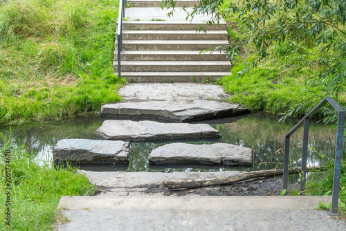 Photography Flat stone slabs cross a narrow stream between concrete stairs