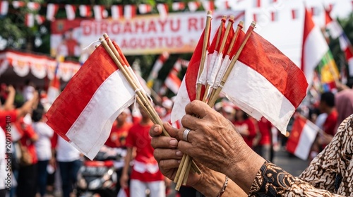 Hands holding small Indonesian flags at a community event.