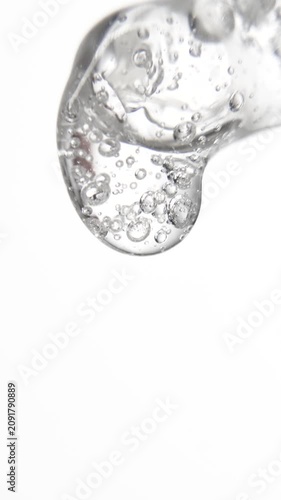 Vertical cosmetic serum fluid gel with bubbles from dropper, pipette over white