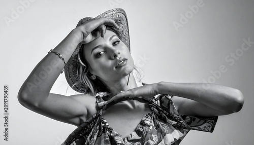 Stylish Young Woman Posing in Straw Hat and Floral Top in Studio Portrait