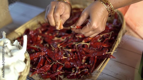 Close up of hands destemming dried red chillies before grinding