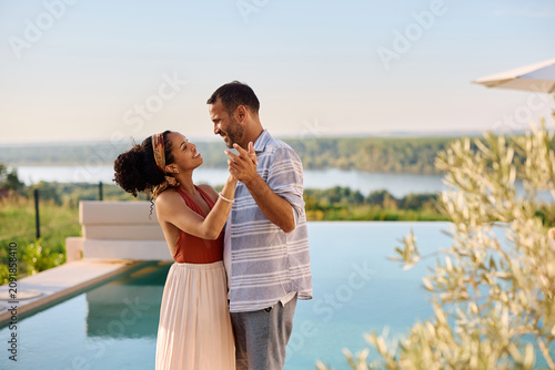 Photos Romantic couple dancing by infinity pool in summer day.