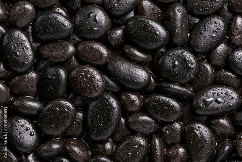 Top view of smooth black spa stones with water droplets