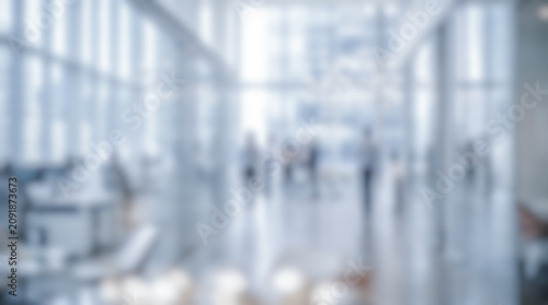 Bright modern blurred office interior background showing professional business people walking corporate workplace setting abstract contemporary room soft natural daylight bokeh