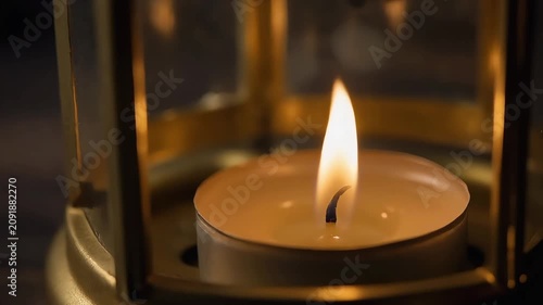 Lit candle in brass lantern with bokeh
