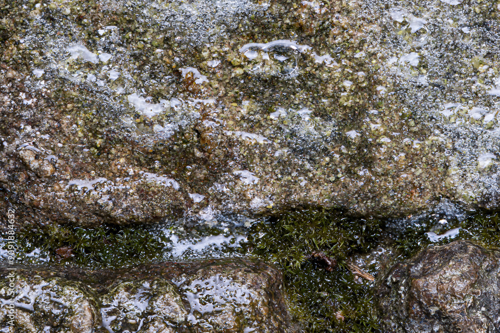 Fototapeta premium Close up of wet stones with green moss and water bubbles