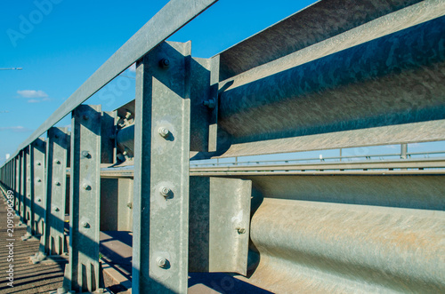 Metal guardrail on a highway structure in bright sunlight showing clear details of design and materials