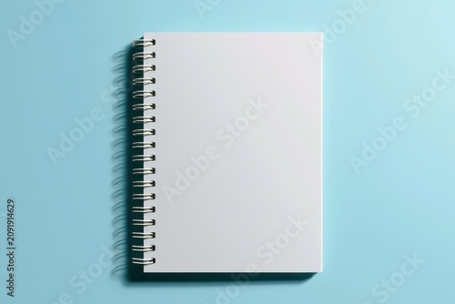 White spiral notebook resting on a pale blue background in a sharp minimalist top view for office stationery and professional branding