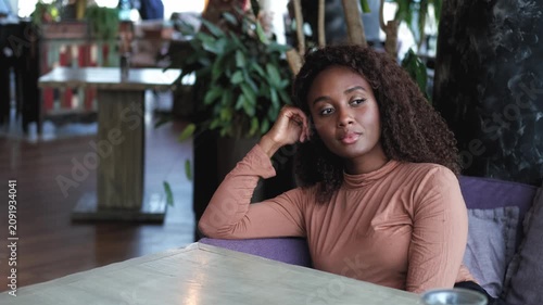 A woman poses in a restaurant. A business student, a young professional, is sitting at a table in a restaurant.