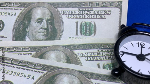 Photos Alarm clock beside one-hundred-dollar banknotes highlights the importance of tim
