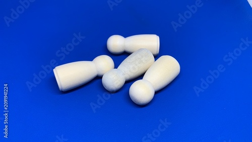 Fotografía Group of wooden peg figures lying on a blue surface, representing inactivity, re